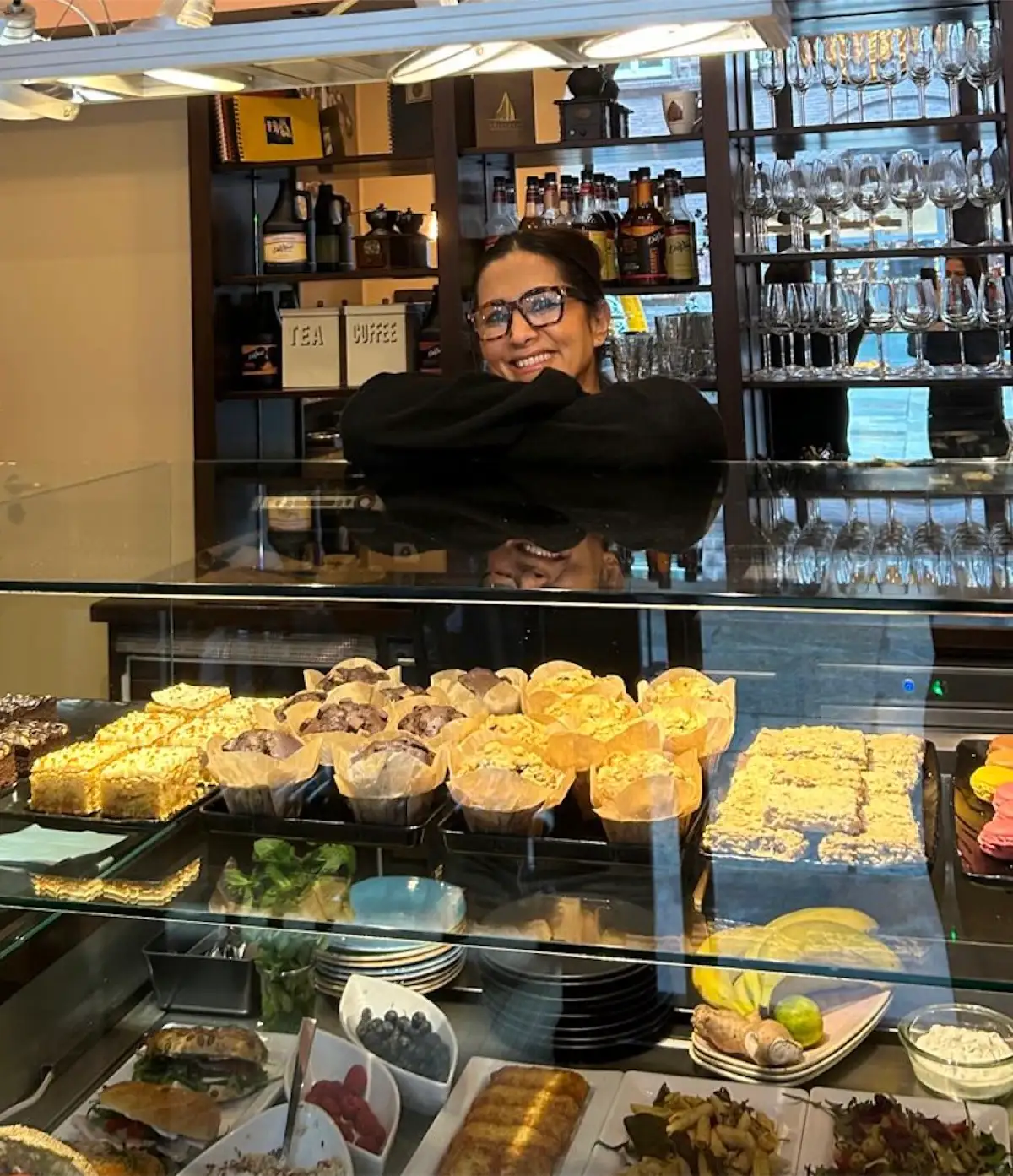 Wajia Ghazi behind the display case with cakes, muffins and sandwiches.
