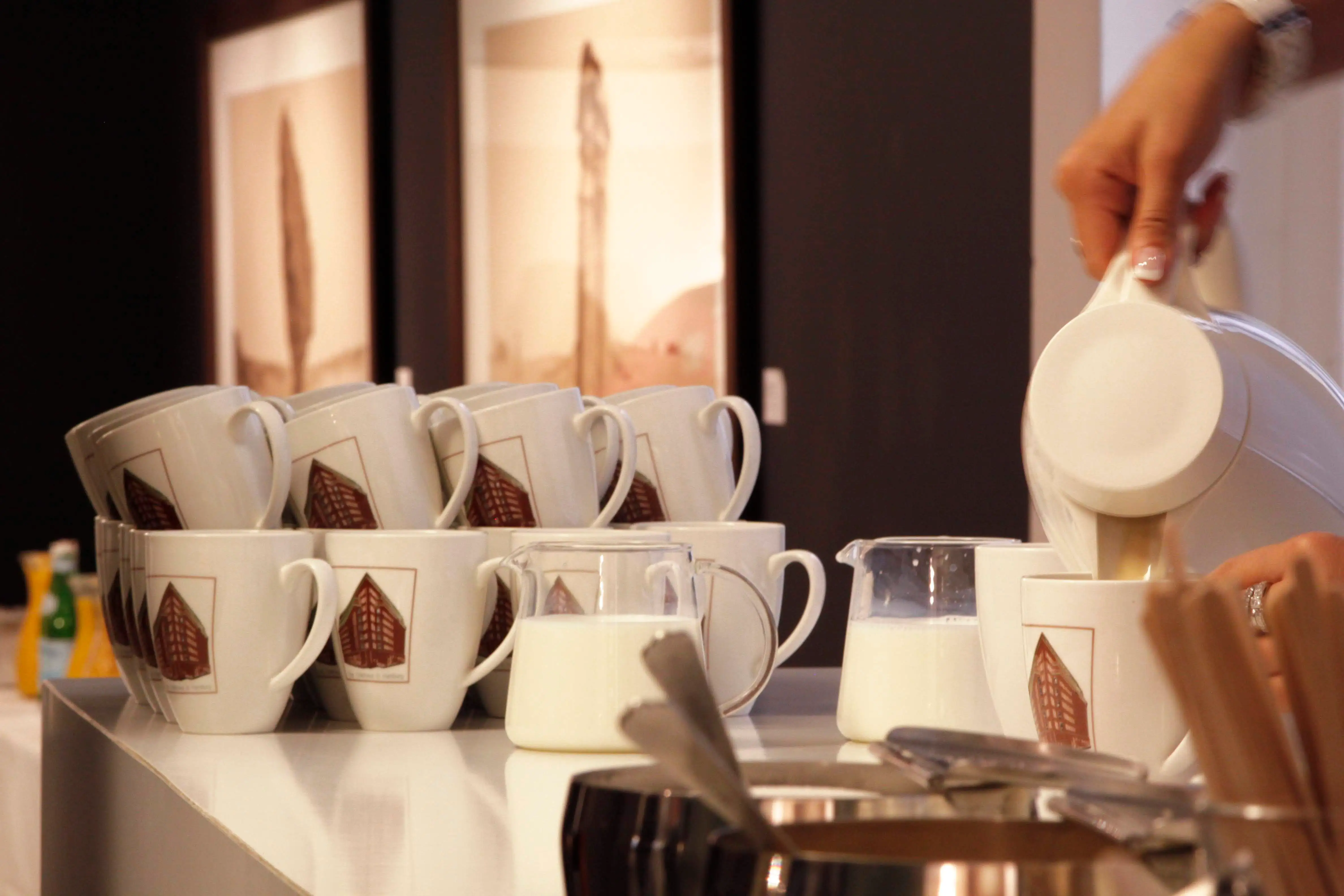 Cups with the Chilehaus motif on the counter, milk being poured